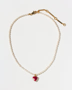 Pearl necklace with a red inverted triangle pendant on a white background