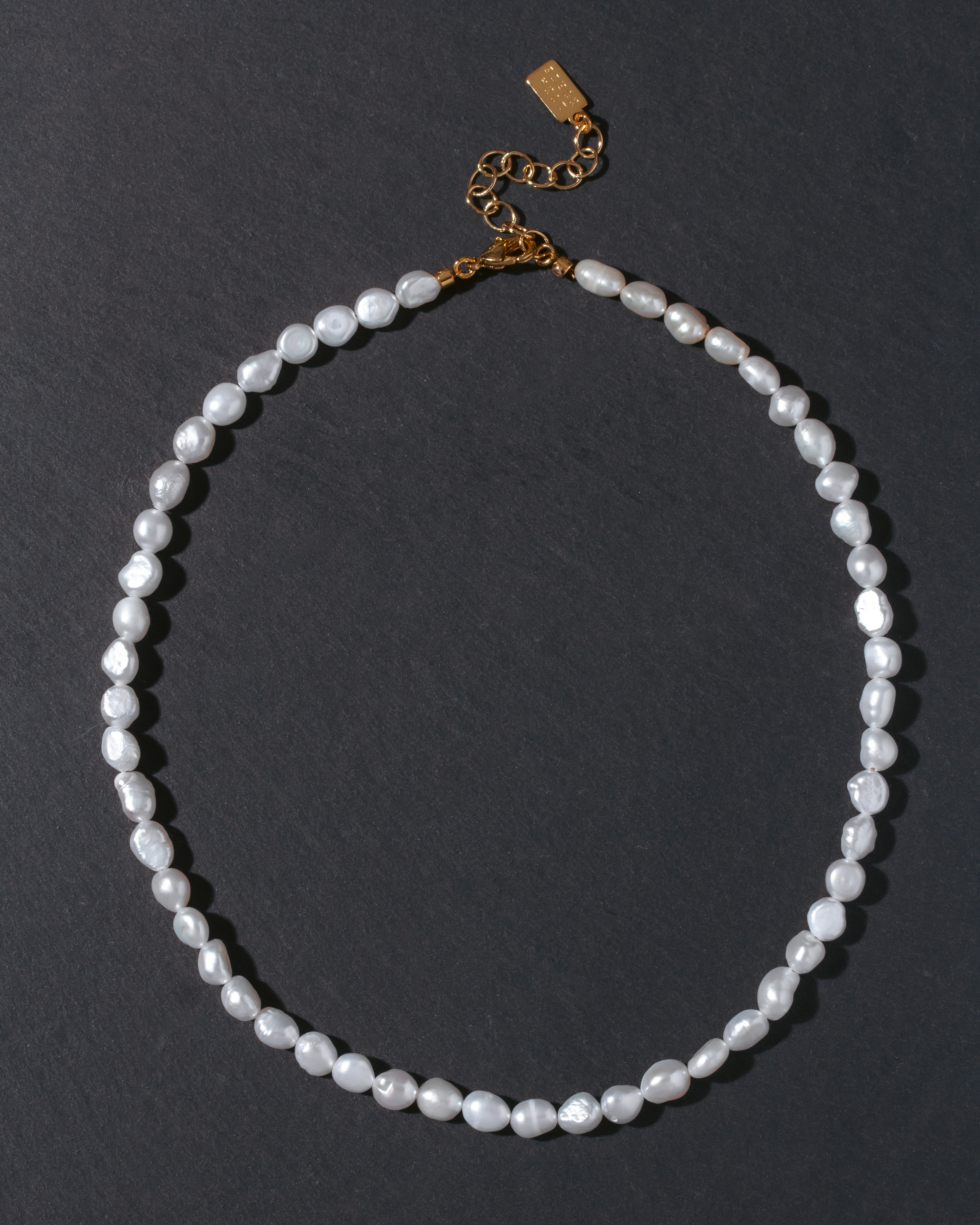 Pearl necklace with a gold clasp on a dark background