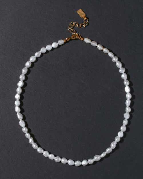 Pearl necklace with a gold clasp on a dark background