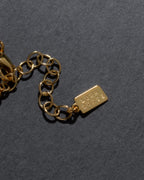 Gold chain extender detail with a Luna Norte tag on a dark gray background