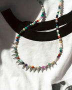Necklace with colorful beads and silver spikes on a white background