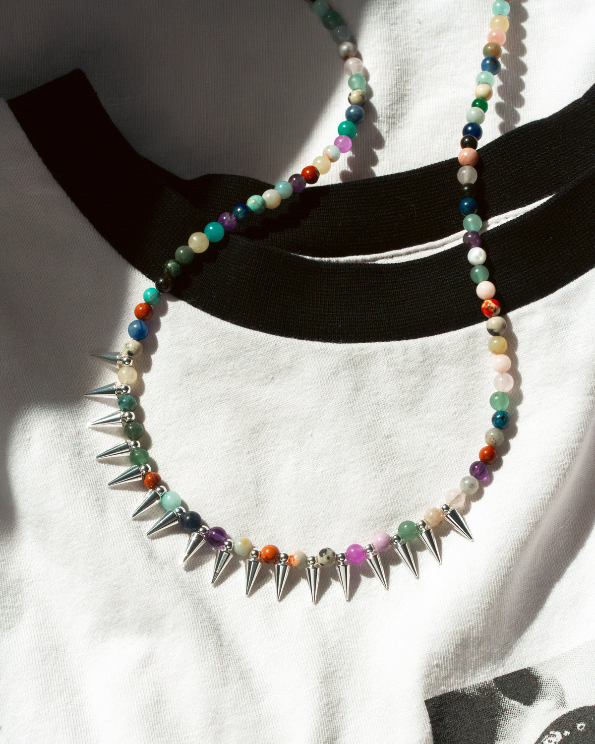 Necklace with colorful beads and silver spikes on a white background