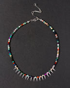 Multicolored beaded necklace with spike details on a dark background