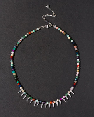 Multicolored beaded necklace with spike details on a dark background
