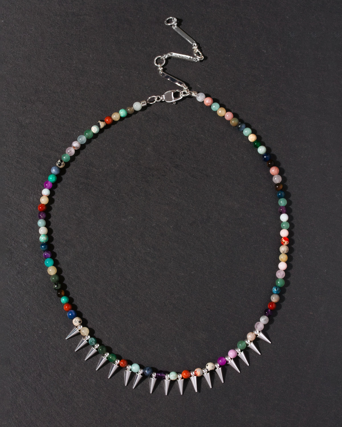Multicolored beaded necklace with spike details on a dark background