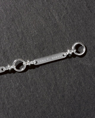 Silver detail of Luna Norte extender chain on a dark background