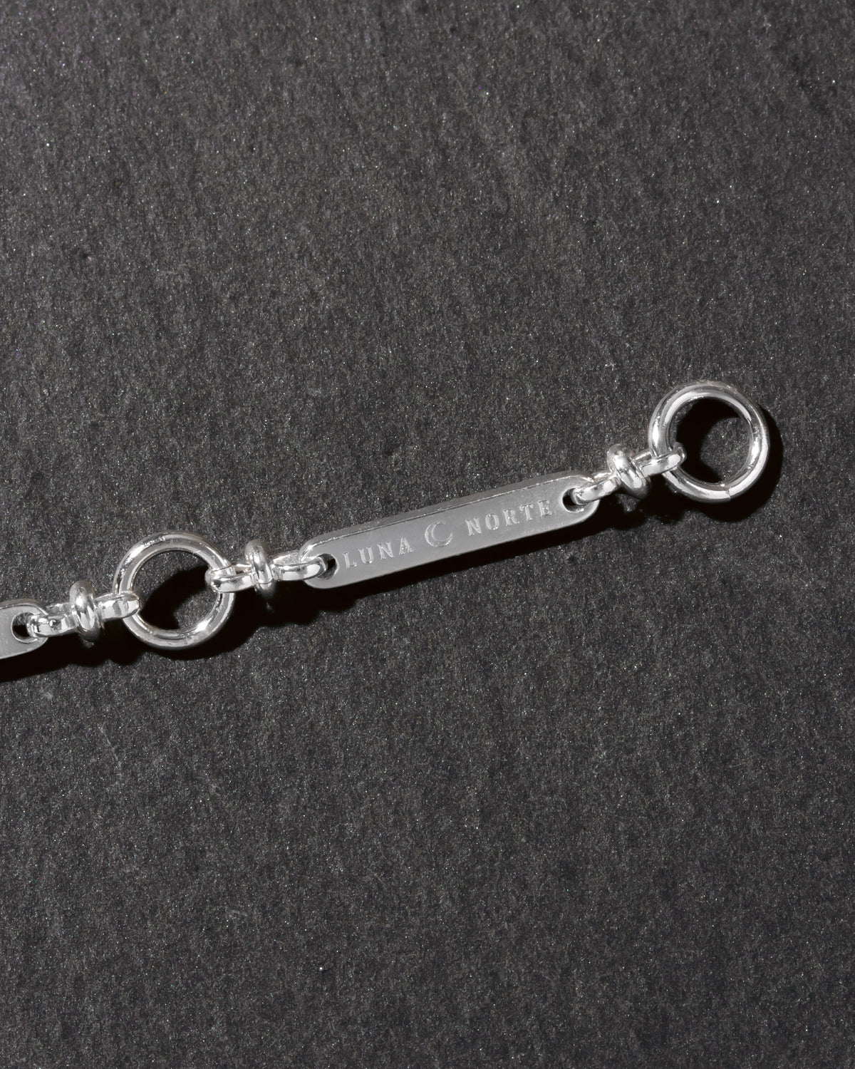 Silver detail of Luna Norte extender chain on a dark background
