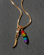 Necklace with gold letter 'j' charm and rainbow beads on a dark background