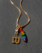 Necklace with gold pendant, rainbow beads, and letter 'W' on a dark background