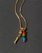 Gold necklace with colorful beads and a letter 'i' charm on a dark background
