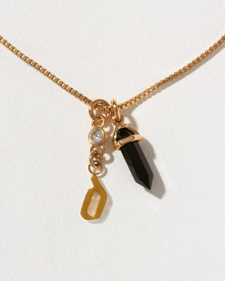 Necklace with gold chain, black crystal pendant, and letter 'd' gold charm on a white background