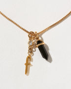 Necklace with gold chain, letter 'f' charm, and black crystal pendant on a white background