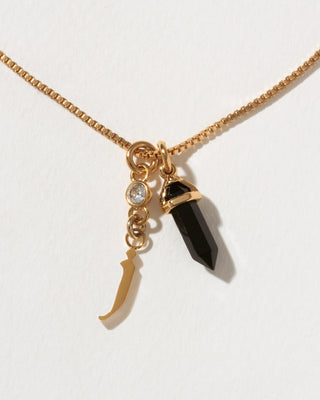 Necklace with gold letter 'j' charm, black crystal pendant, and small round CZ charm on a white background