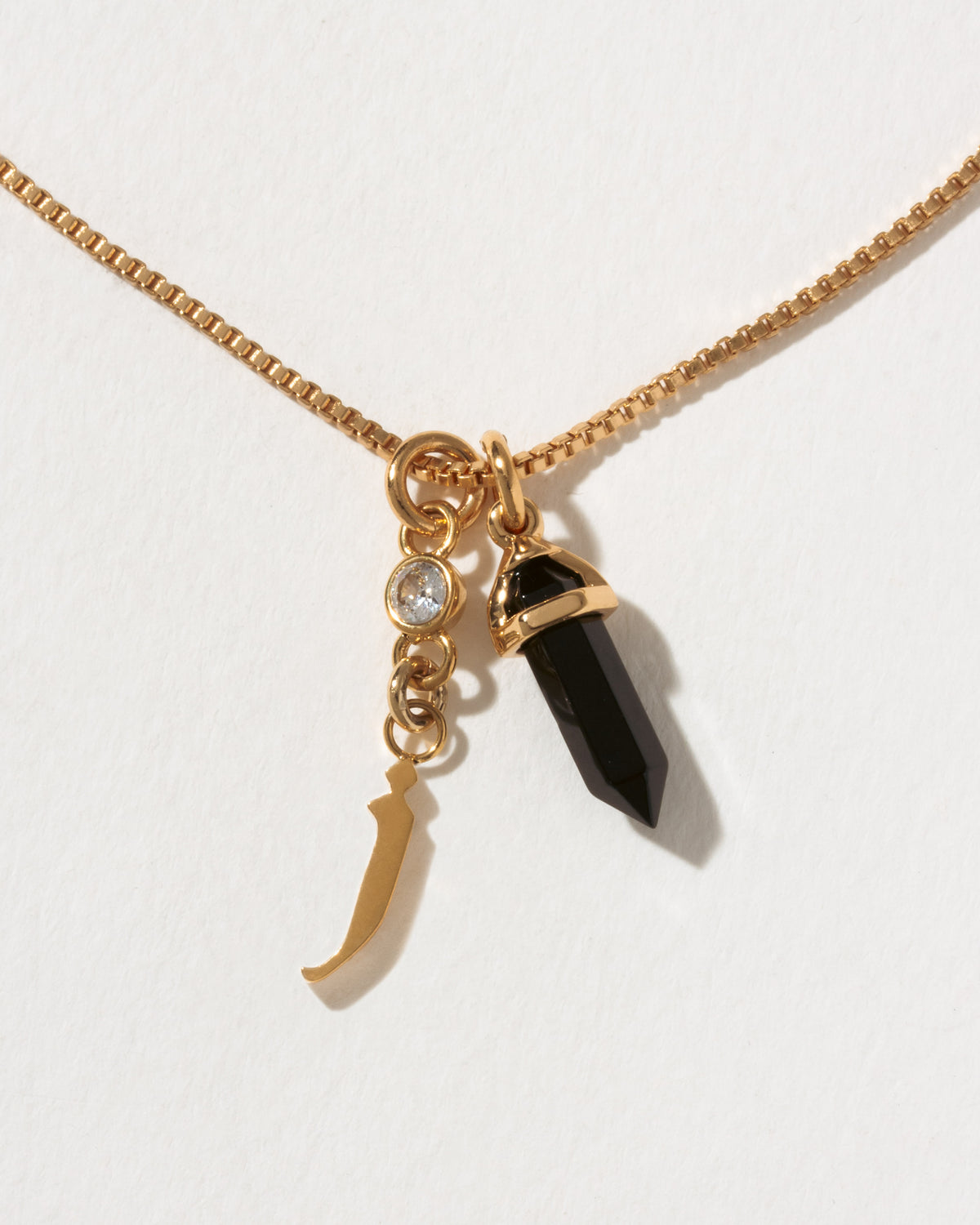 Necklace with gold letter 'j' charm, black crystal pendant, and small round CZ charm
