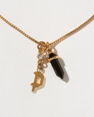 Necklace with gold chain, letter 'P' charm, and black crystal pendant on a white background