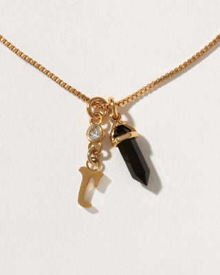 Necklace with gold chain, black crystal pendant, and gold 'r' charm on a white background