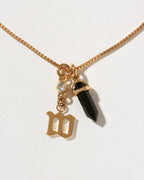 Necklace with gold charm, black crystal, and letter 'W' on a white background
