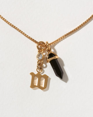 Necklace with gold charm, black crystal, and letter 'W' on a white background