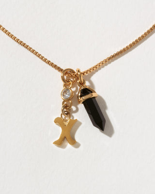 Necklace with gold chain, black crystal pendant, and gold 'X' charm on a white background