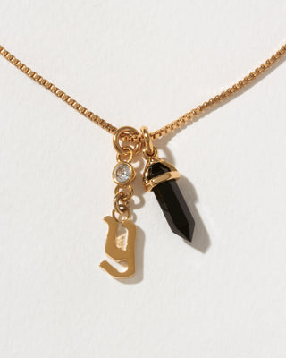 Necklace with gold charm, black crystal, and letter 'y' on a white background