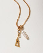 Gold box chain necklace with a lowercase letter "h" charm, a clear crystal, and an long pearl.