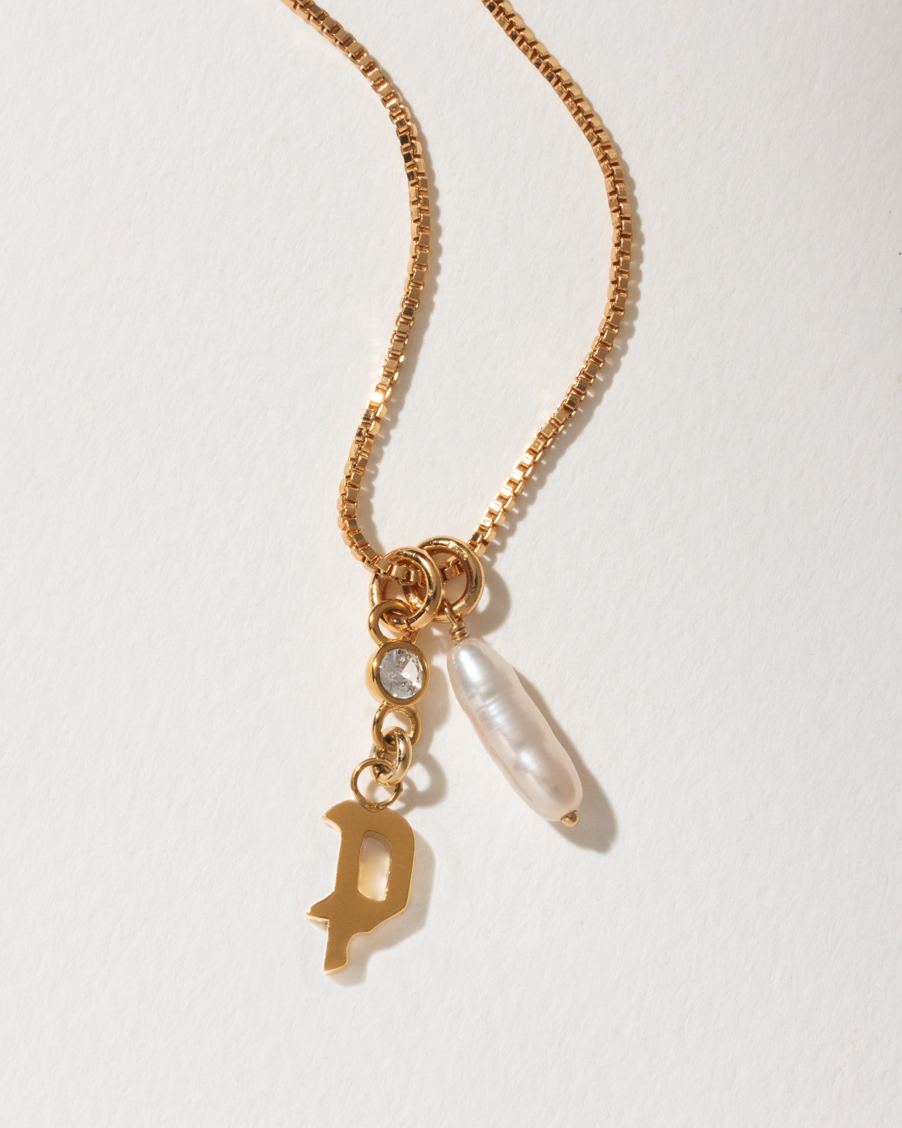 Gold necklace with baroque pearl, clear crystal, and P charm.