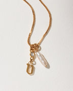 Gold box chain necklace with a gold letter U initial, a small clear crystal, and an pearl charm.