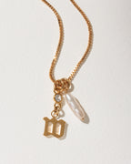 Gold necklace with an Old English letter M pendant, a baroque pearl, and clear crystal.