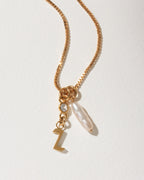 Gold box chain necklace with a "Z" initial charm, a small clear crystal, and an long pearl pendant.