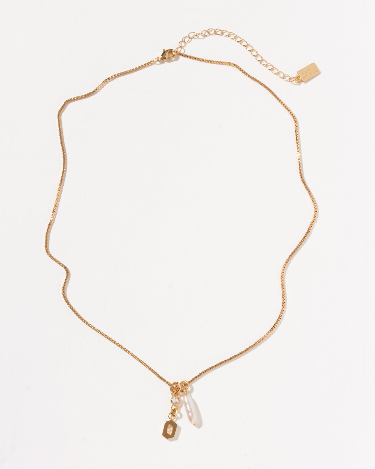 Gold box chain necklace with a small crystal, a pearl charm, and a gold letter O initial pendant.