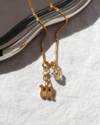 Gold necklace with lowercase m charm, a clear CZ accent, and Herkimer quartz.