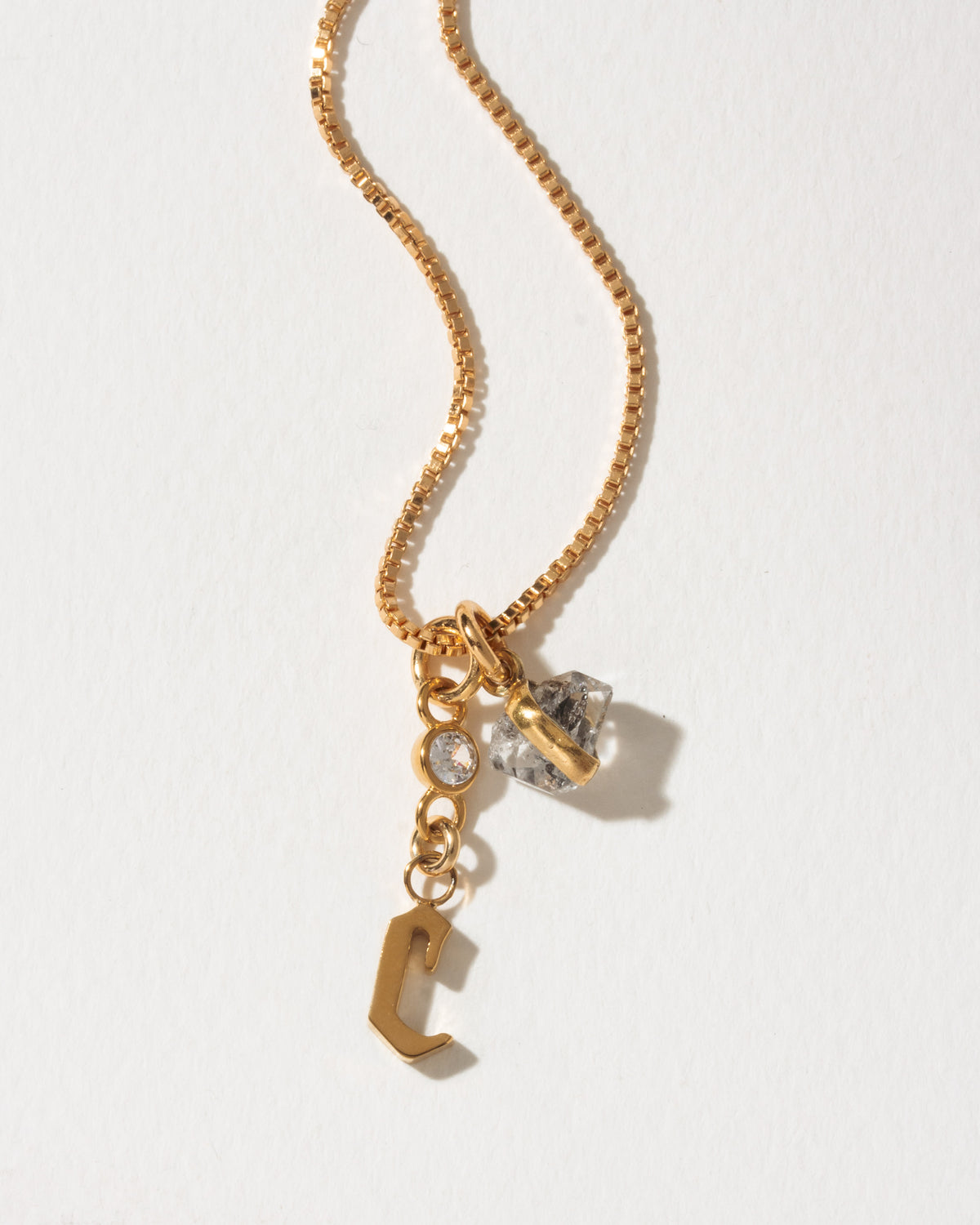 Gold necklace with letter C pendant, clear crystal, and Herkimer quartz.