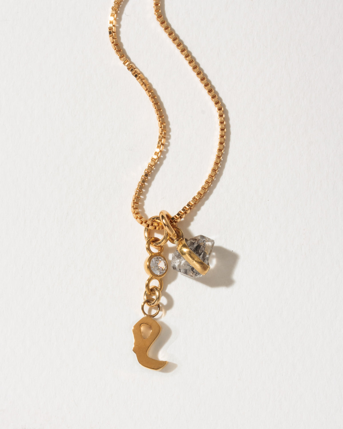 Gold necklace with cursive L charm, clear crystal, and Herkimer quartz.