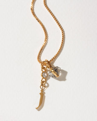 Gold box chain necklace featuring a small crystal, a herkimer quartz crystal pendant, and a gold letter J initial charm.