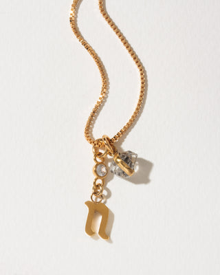 Gold box chain necklace featuring a gold lowercase letter n pendant, a small clear gem, and a herkimer quartz charm.