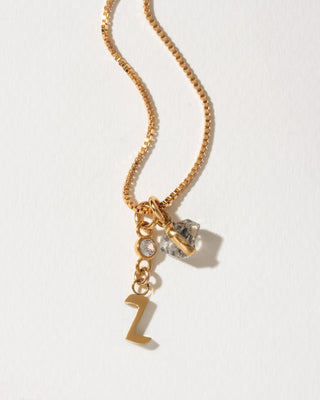 Gold box chain necklace featuring a letter Z charm, a herkimer quartz charm, and a small bezel-set clear stone.
