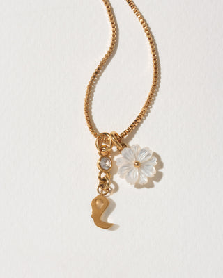 Gold necklace with a flower and letter 'e' charm on a light background