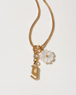 Gold necklace with a flower and letter 'Y' charm on a light background