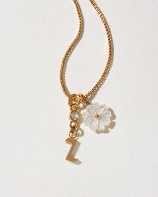 Gold necklace with a flower charm and letter 'Z' on a light background
