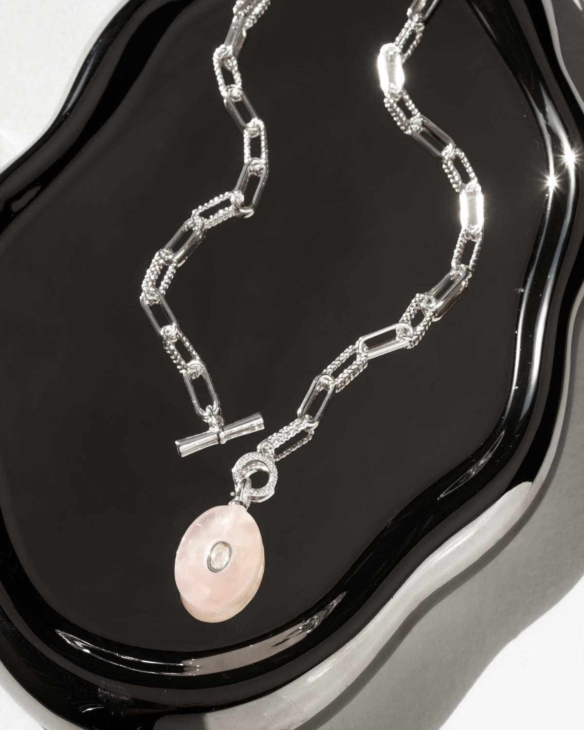 Silver plated paperclip toggle front necklace with pink rose quartz oval pendant with clear center bezeled stone.