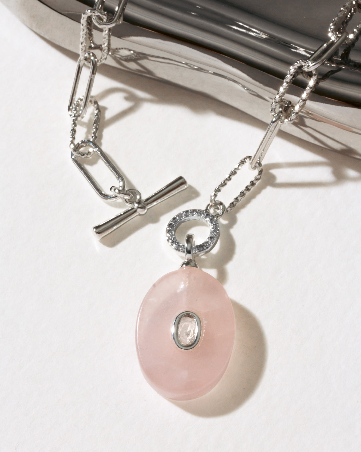 Silver plated paperclip toggle front necklace with pink rose quartz oval pendant with clear center bezeled stone.
