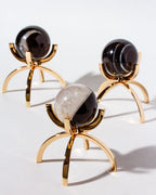 Three dark and light crystal spheres on minimalist gold stands