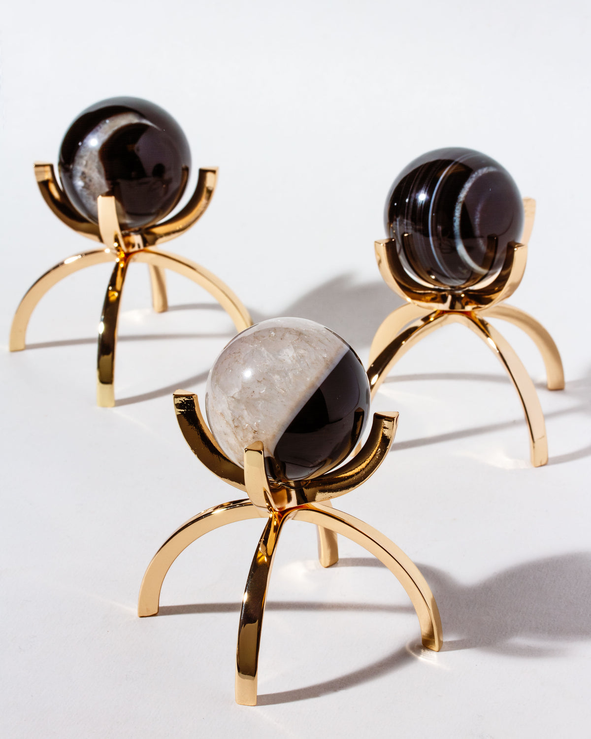 Three dark and light crystal spheres on minimalist gold stands