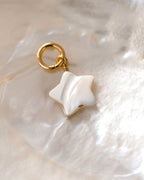 Star shaped mother of pearl gold hoop earring on a white shell.
