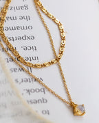 Layering gold necklace with a small opal pendant on an open book