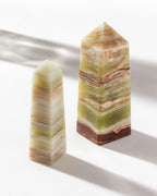 Medium and large calcite obelisks standing next to each other on a white surface.