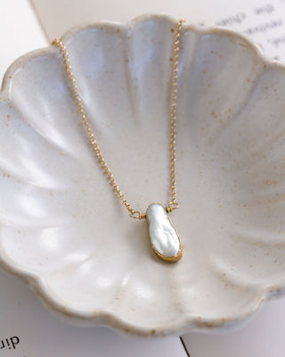 Necklace with a baroque Mother of pearl  pendant on a ceramic dish