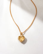 Gold necklace with a heart-shaped citrine pendant on a white background