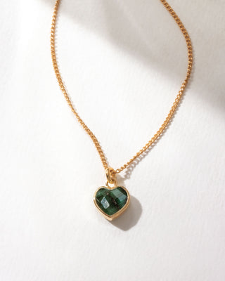 Gold necklace with a dark green emerald heart-shaped pendant on a white background