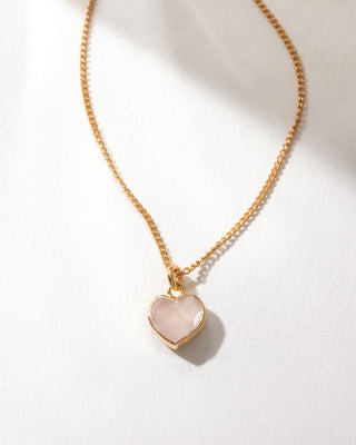 Gold necklace with a heart-shaped pink rose quartz pendant on a white background
